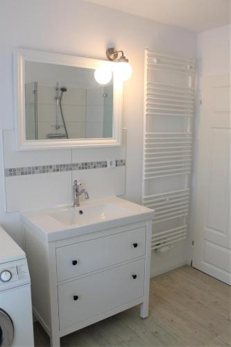a white bathroom with a sink and a mirror at Tant Berta´s Huus in Krummhörn