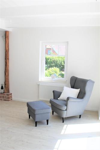 a living room with a chair and a stool at Tant Berta´s Huus in Krummhörn