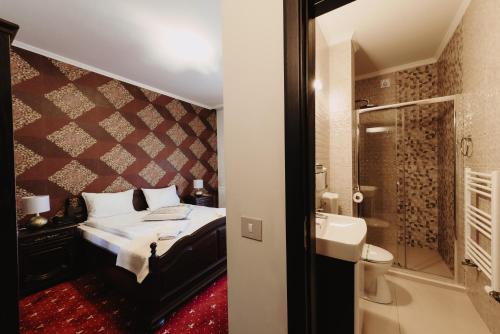 sypialnia z łóżkiem oraz łazienka z prysznicem w obiekcie Aries Vârtop w mieście Vartop