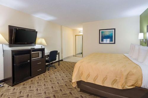 a hotel room with a bed and a flat screen tv at Quality Inn Tanglewood in Roanoke