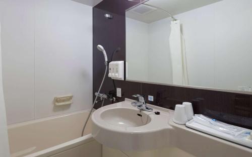 
a bathroom with a sink, mirror and bath tub at Comfort Hotel Hakata in Fukuoka
