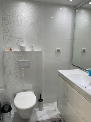 a white bathroom with a toilet and a sink at סוויטת תשוקה על הים - Passion Suite by the Sea in Bat Yam