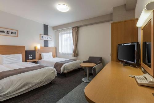 Habitación de hotel con 2 camas y TV de pantalla plana. en Comfort Hotel Sendai East, en Sendai