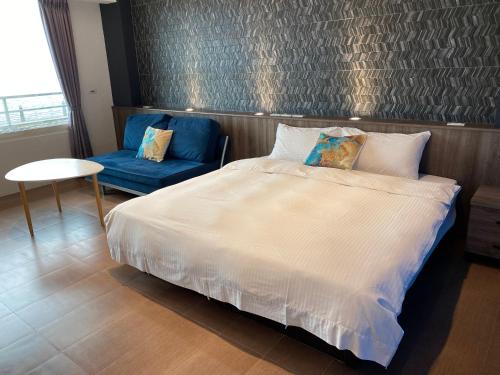 a bedroom with a white bed and a blue chair at 36 Lighthouse in Hualien City