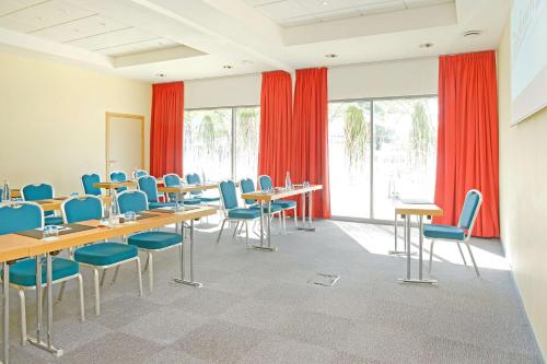 a room with tables and chairs and red curtains at Radisson Blu Hotel Toulouse Airport in Blagnac