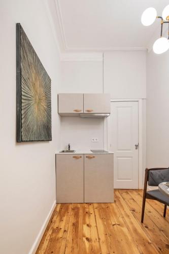 a kitchen with white walls and a wooden floor at Petit studio Rosa - Bairro Alto in Lisbon
