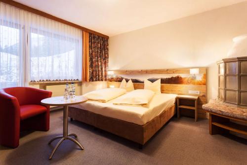 a hotel room with a bed and a red chair at Hotel Talhof Garni&more in Wängle bei Reutte in Reutte