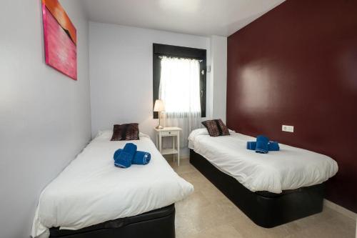 2 łóżka w pokoju z niebieskimi poduszkami w obiekcie LAS VISTAS 2C MENYBER w mieście Nerja