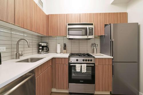 
a kitchen with a stove, refrigerator, microwave and sink at The Beekman Tower, Trademark Collection by Wyndham in New York

