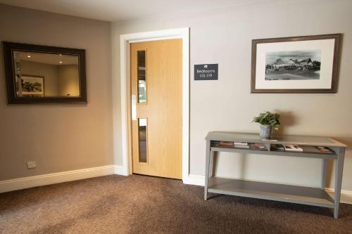 a hallway with a table and a mirror and a door at The Bridge House; BW Signature Collection in Ferndown