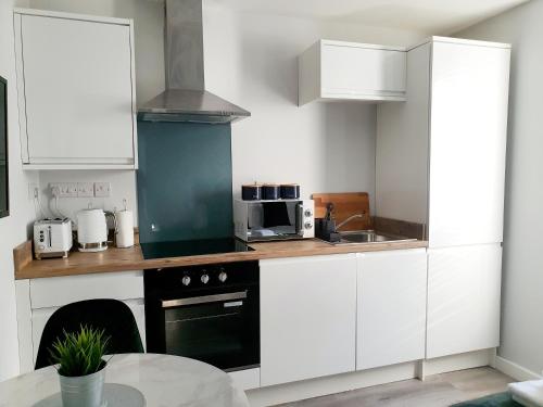 uma cozinha com armários brancos e um forno preto em Modern Town Centre Studio Close to Beach em Bournemouth