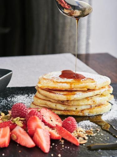 a stack of pancakes with strawberries and syrup on a table at Hotel & Medi-Spa Biały Kamień in Świeradów-Zdrój