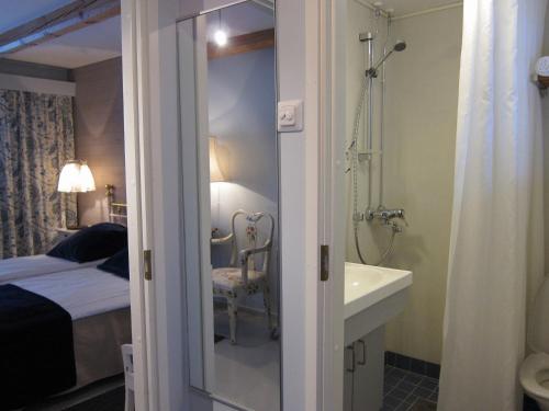 a bathroom with a shower and a sink next to a bed at Tertin Kartano in Mikkeli