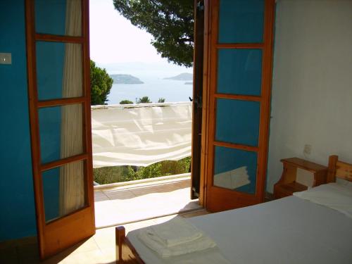 a bedroom with an open door with a view of the ocean at Anemos Studios in Vassilias