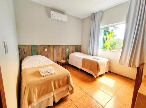 een hotelkamer met 2 bedden en een raam bij Pousada Villa Magna - Chalé Família in Diamantina