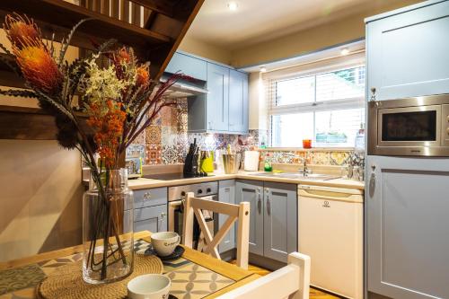 a kitchen with blue cabinets and a table with a vase of flowers at Sorley Boys Snug in Derry Londonderry