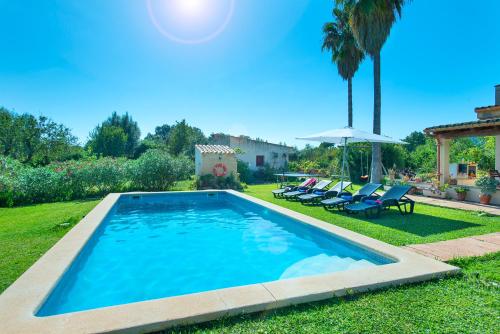 a swimming pool in a yard with chairs and an umbrella at Owl Booking Villa Punta Magdalena - Family Holidays in Pollença