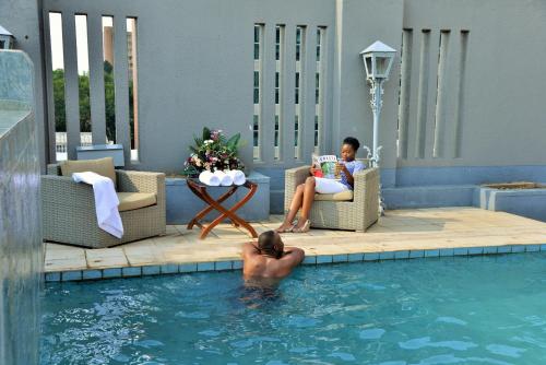 un hombre leyendo un libro en la piscina en Cresta Jameson Hotel, en Harare