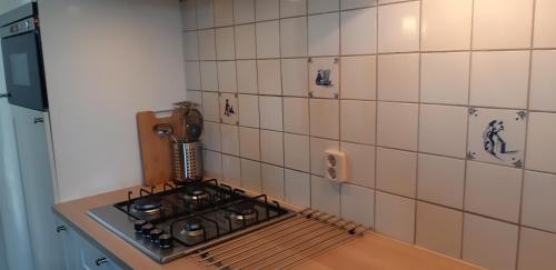 een keuken met een fornuis en een betegelde muur bij Bij De Vuurtoren in Hollum