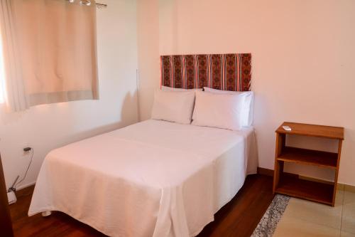 a bedroom with a white bed with a night stand at Flat AGC in Morro de São Paulo