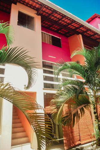 a building with palm trees in front of it at Flat AGC in Morro de São Paulo