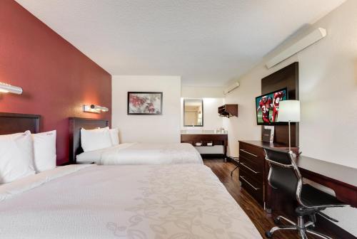 a hotel room with two beds and a desk at Super 8 by Wyndham Deerfield - Northbrook in Deerfield