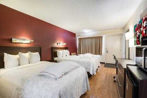 a hotel room with two beds and a television at Super 8 by Wyndham Deerfield - Northbrook in Deerfield