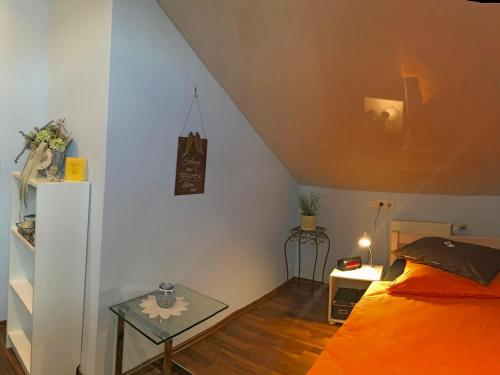 sypialnia z pomarańczowym łóżkiem i stołem w obiekcie Ferienwohnung Elisabeth w mieście Burgbernheim