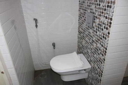 a bathroom with a white toilet and a tile wall at Hotel SK Riverfront in Vijayawāda