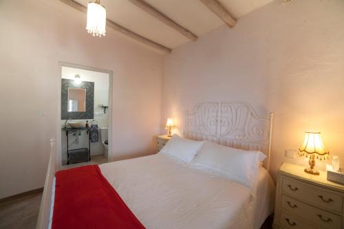 1 dormitorio con cama blanca y manta roja en Cortijo Privilegio, en Lanjarón