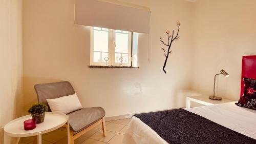a bedroom with a bed and a chair and a window at Bicos S by Check-in Portugal in Albufeira