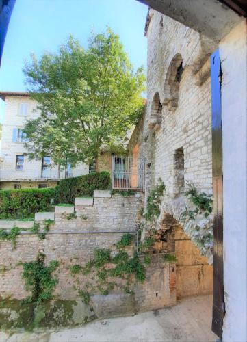 an old brick building with stairs and a tree at Hotel San Francesco e il lupo in Gubbio