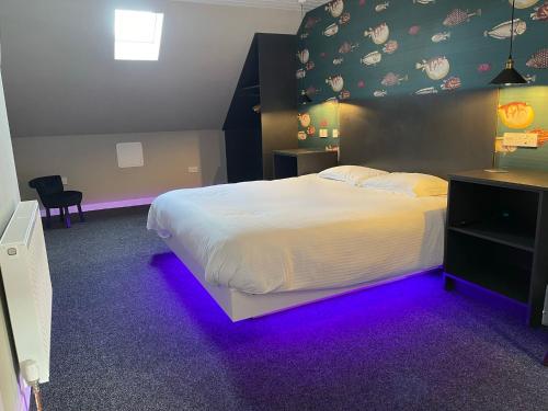 a bedroom with a white bed with purple lighting at The Inn @ Y-Not in Thurso