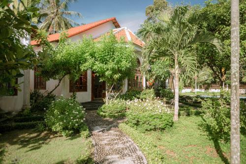 una casa con un jardín con palmeras enfrente en Wings Bungalow en Phu Quoc