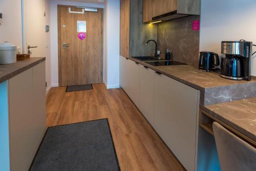 cocina con armarios blancos y suelo de madera en VacationClub – Jantaris Apartament A24, en Mielno