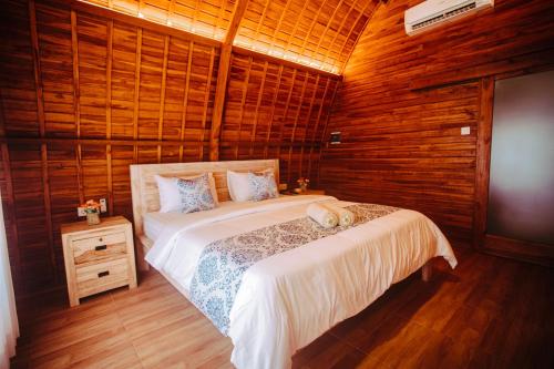 a bedroom with a bed in a room with wooden walls at Druwa Bali in Uluwatu