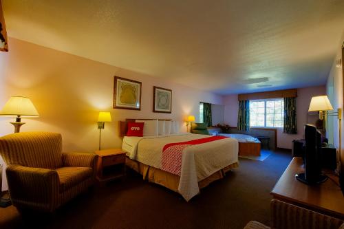 a hotel room with a bed and a chair at Hotel O Eureka Springs - Christ of Ozark Area in Eureka Springs