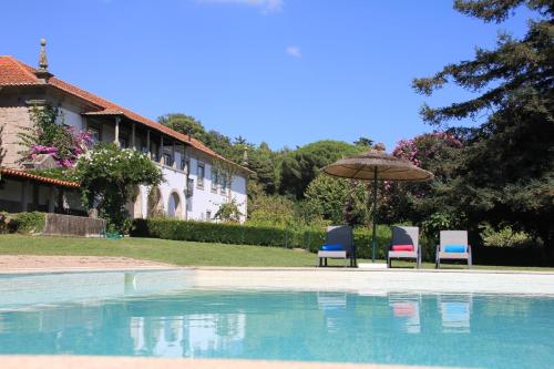 two chairs and an umbrella next to a swimming pool at Quinta De Guimaraes in Miguas