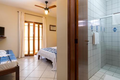 a bathroom with a shower and a bed in a room at Pousada Mar Azul in Ubatuba