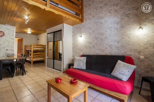 a living room with a red couch and a table at La Tomba Val-Cenis Lanslevillard in Lanslevillard