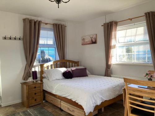 ein Schlafzimmer mit einem Bett und zwei Fenstern in der Unterkunft Binnian Gateway in Ballymartin