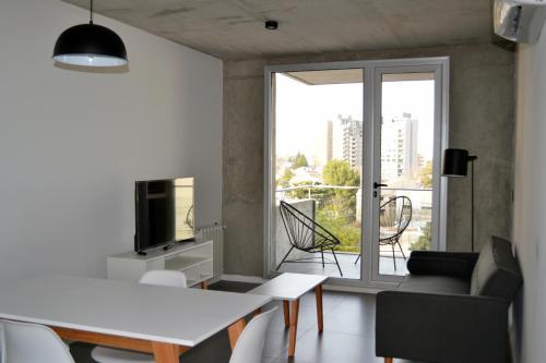 uma sala de estar com uma mesa, uma televisão e uma janela em Loi Flats Edificio Tucuman em Neuquén