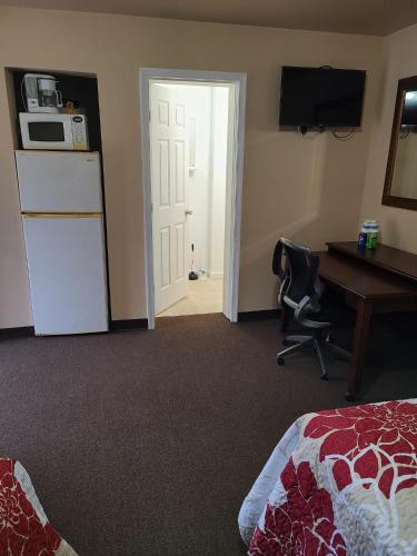 a room with a bed and a desk and a refrigerator at Clarysville Motel in Frostburg