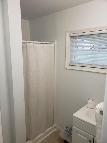a white bathroom with a shower and a sink at Clarysville Motel in Frostburg