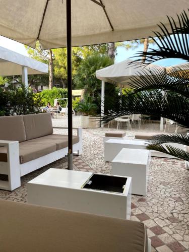 a patio with a couch and tables and an umbrella at Hotel Franca in Milano Marittima