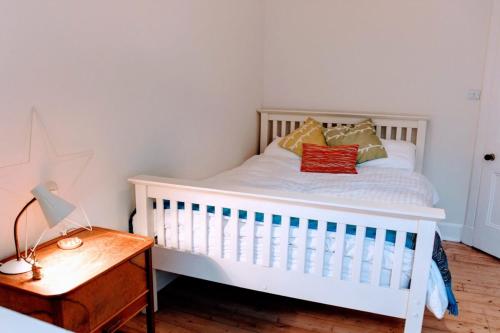 ein weißes Kinderbett in einem Schlafzimmer mit einem Holztisch in der Unterkunft Bright Modern Arthurs Seat 2 Bedroom Apartment in Edinburgh