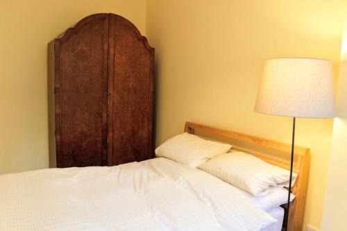 Bett mit einem Kopfteil aus Holz neben einer Lampe in der Unterkunft Bright Modern Arthurs Seat 2 Bedroom Apartment in Edinburgh