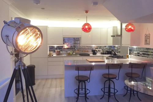 a kitchen with a counter with stools and a light at Spacious 1 Bedroom Split Level Old Pub Conversion Tower Bridge in London