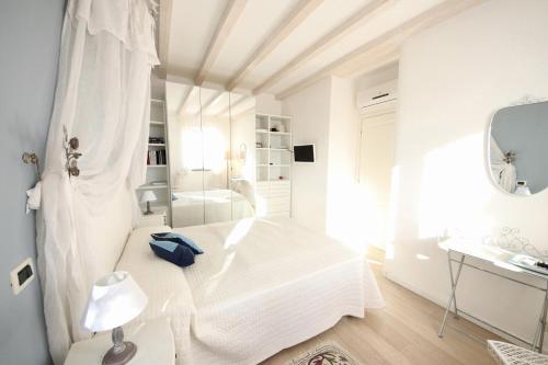 een witte slaapkamer met een wit bed en een spiegel bij VILLA BELVEDERE by KlabHouse in Santa Margherita Ligure