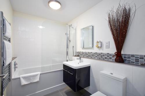 a white bathroom with a sink and a toilet at Swan Place Apartments By Viridian Apartments in Swindon